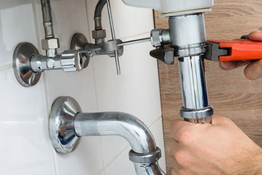 Plumber working on pipes in a bathroom